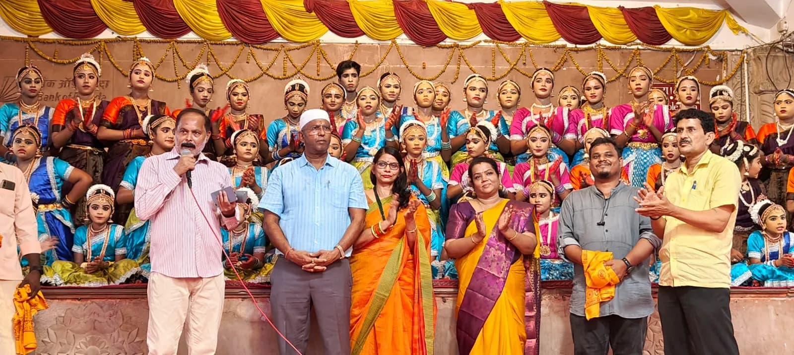 Dignitaries applauding young dancers on a decorated festival stage — Uddharsha Foundation community festival